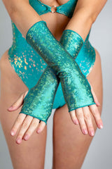 A woman's hands, crossed at the wrists, wearing holographic teal gloves.