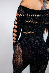 Off-shoulder black jumpsuit with rhinestone details and cutouts, perfect for rave outfits.