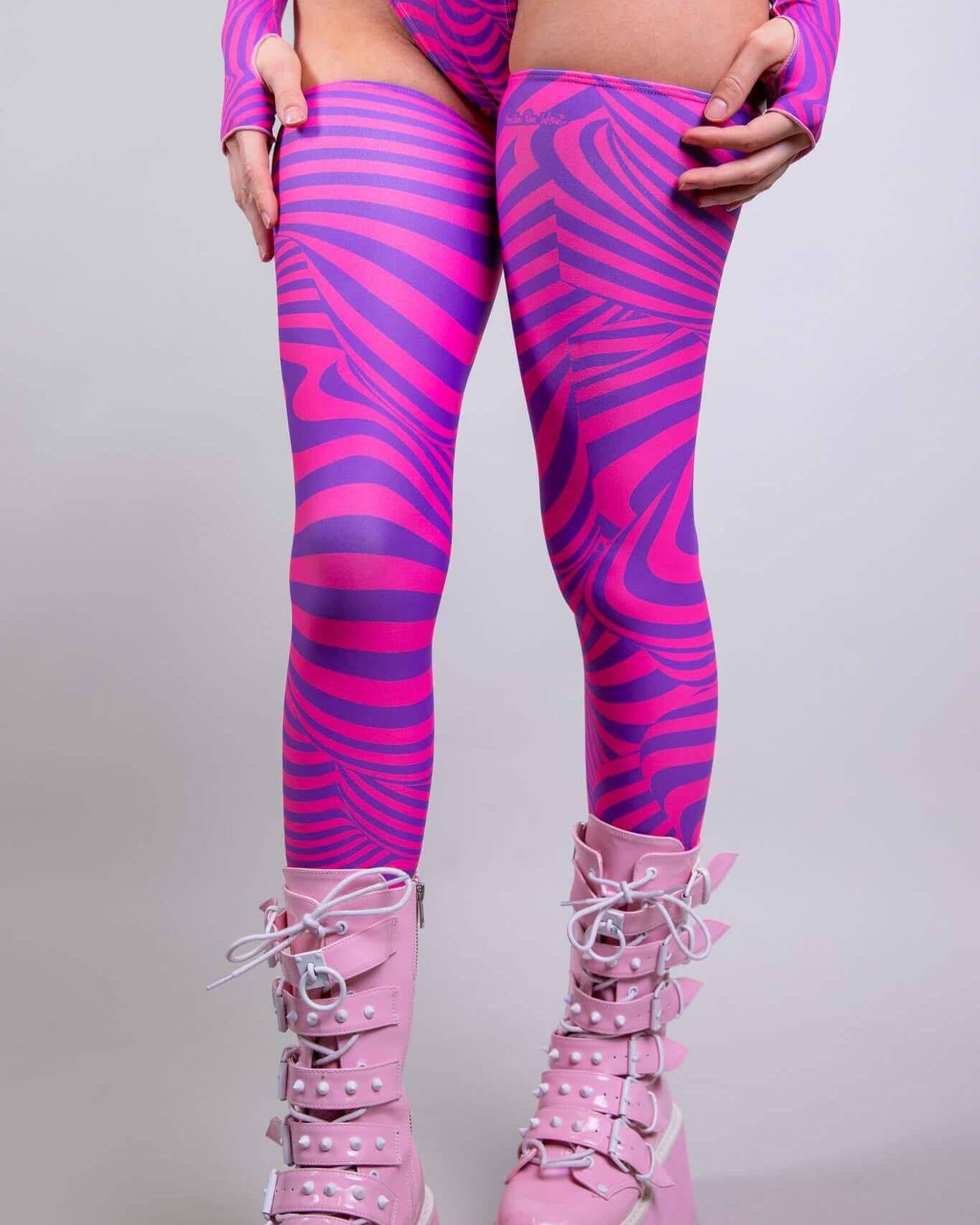 Pink and purple striped Cheshire leg sleeves paired with trendy platform boots, perfect for rave outfits.