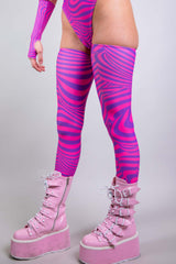 An up close photo of a woman's legs. She is wearing pink boots with pink and purple swirled leg sleeves that go up to her upper thigh.