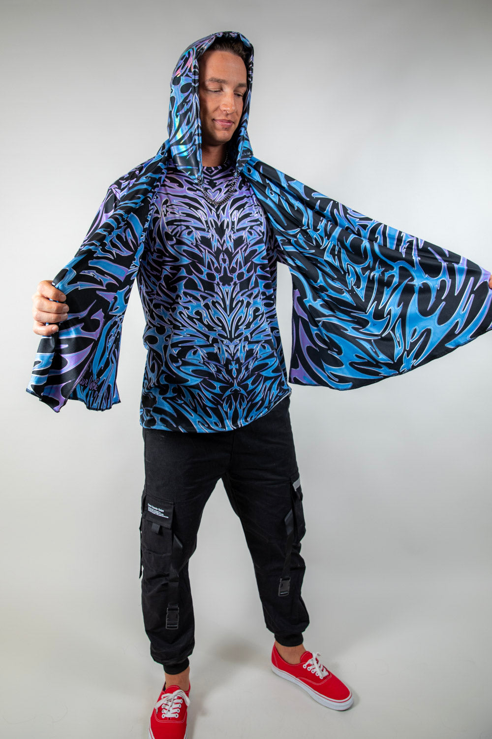 Model wearing the Chromium Festival Scarf with arms spread wide, showcasing its bold cyber sigalism print and hooded design.