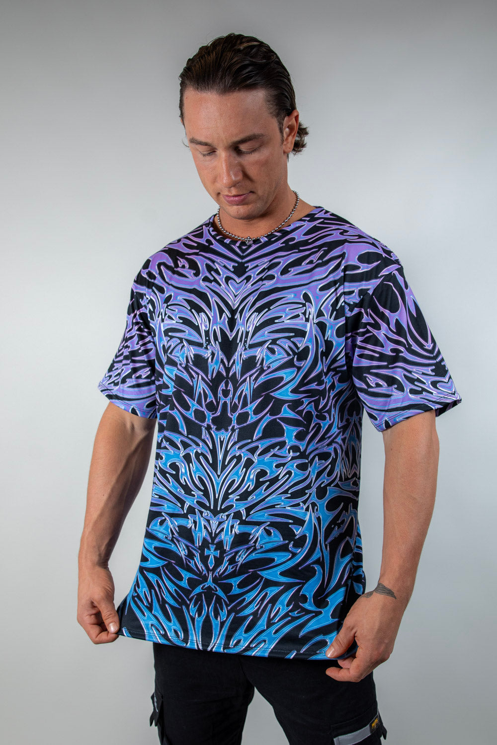 Model showcasing the Chromium Oversized Softee from a slight angle, highlighting its relaxed, draped fit and bold holographic design.