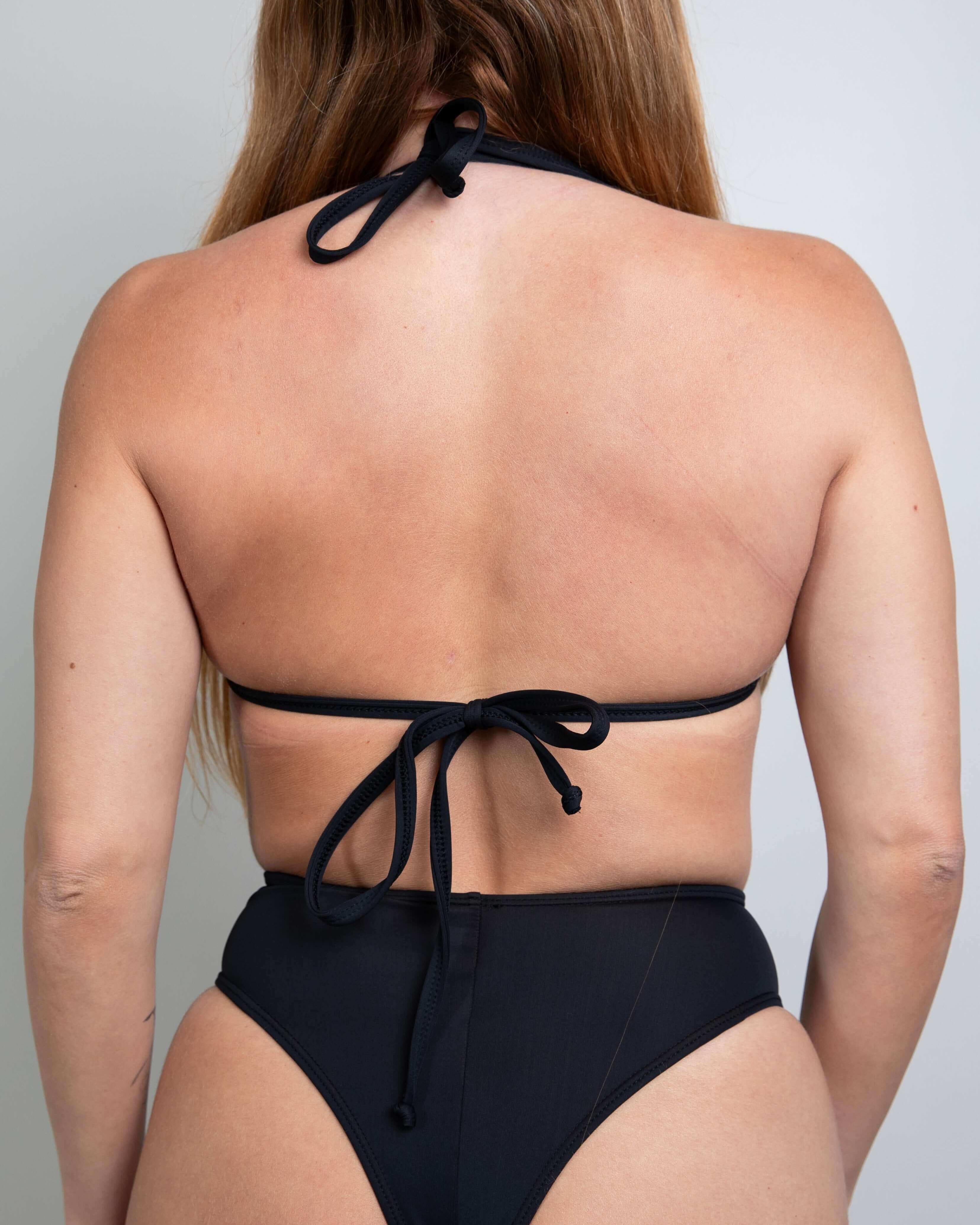 Back view of a woman wearing a black triangle bikini top with tie straps, perfect for rave outfits.