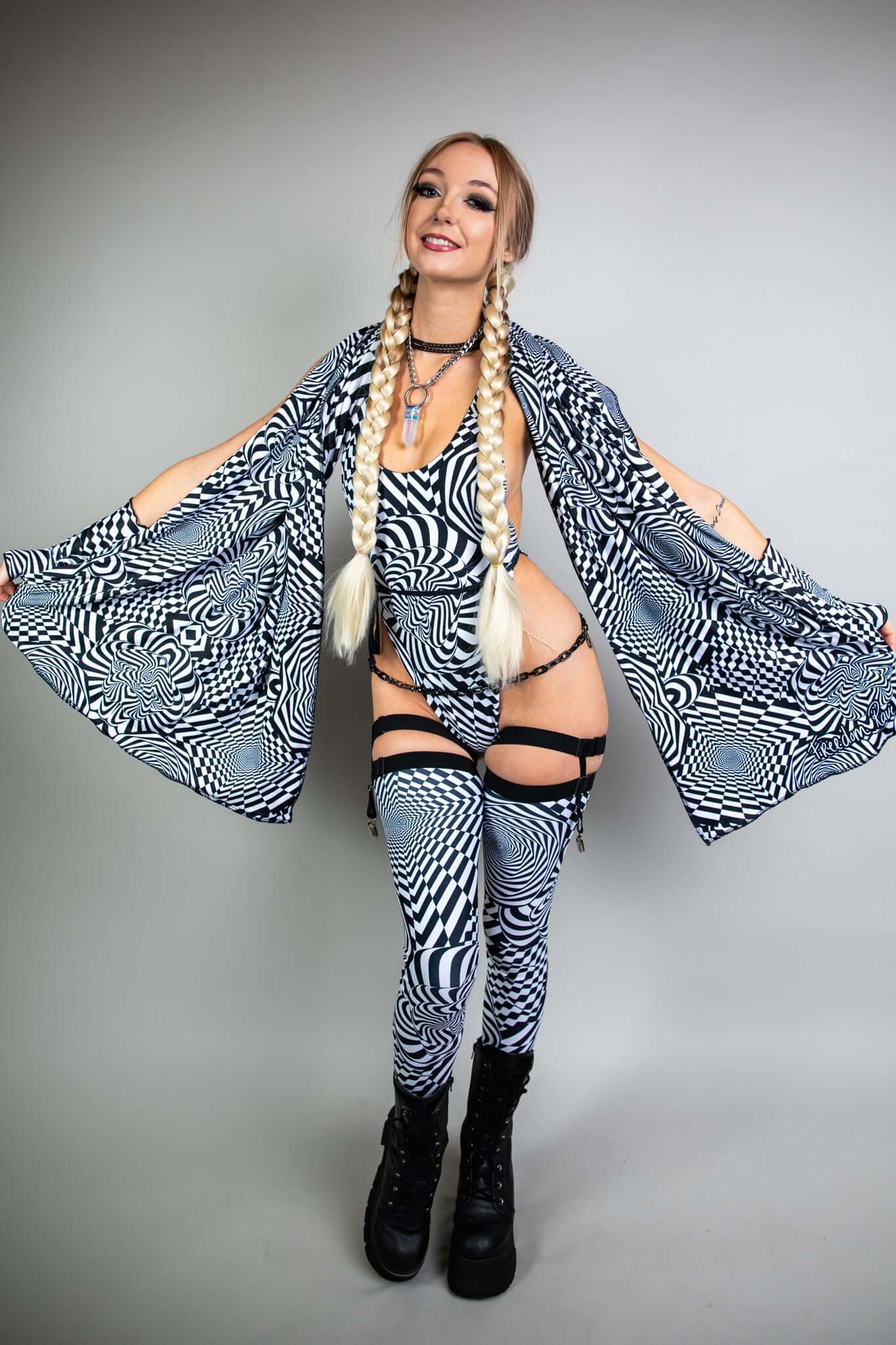 A woman wearing a black and white geometric printed bodysuit with a matching pashmina draped over her shoulders.