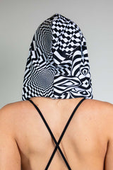 A woman wearing a black and white geometric printed hood and matching bodysuit. She is facing away from the camera.