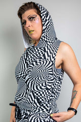 A person with unique makeup wearing a black and white geometric printed hooded tank top and matching pants.