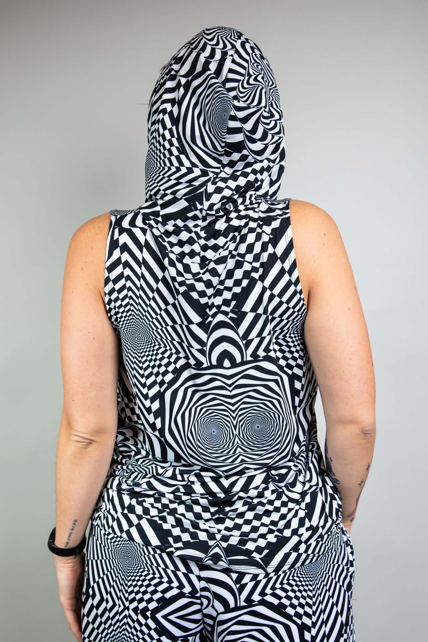 A person wearing a black and white geometric printed hooded tank top and matching pants. They are facing away from the camera.