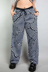 An up close photo of a woman wearing wide legged pants with a black and white geometric pattern.