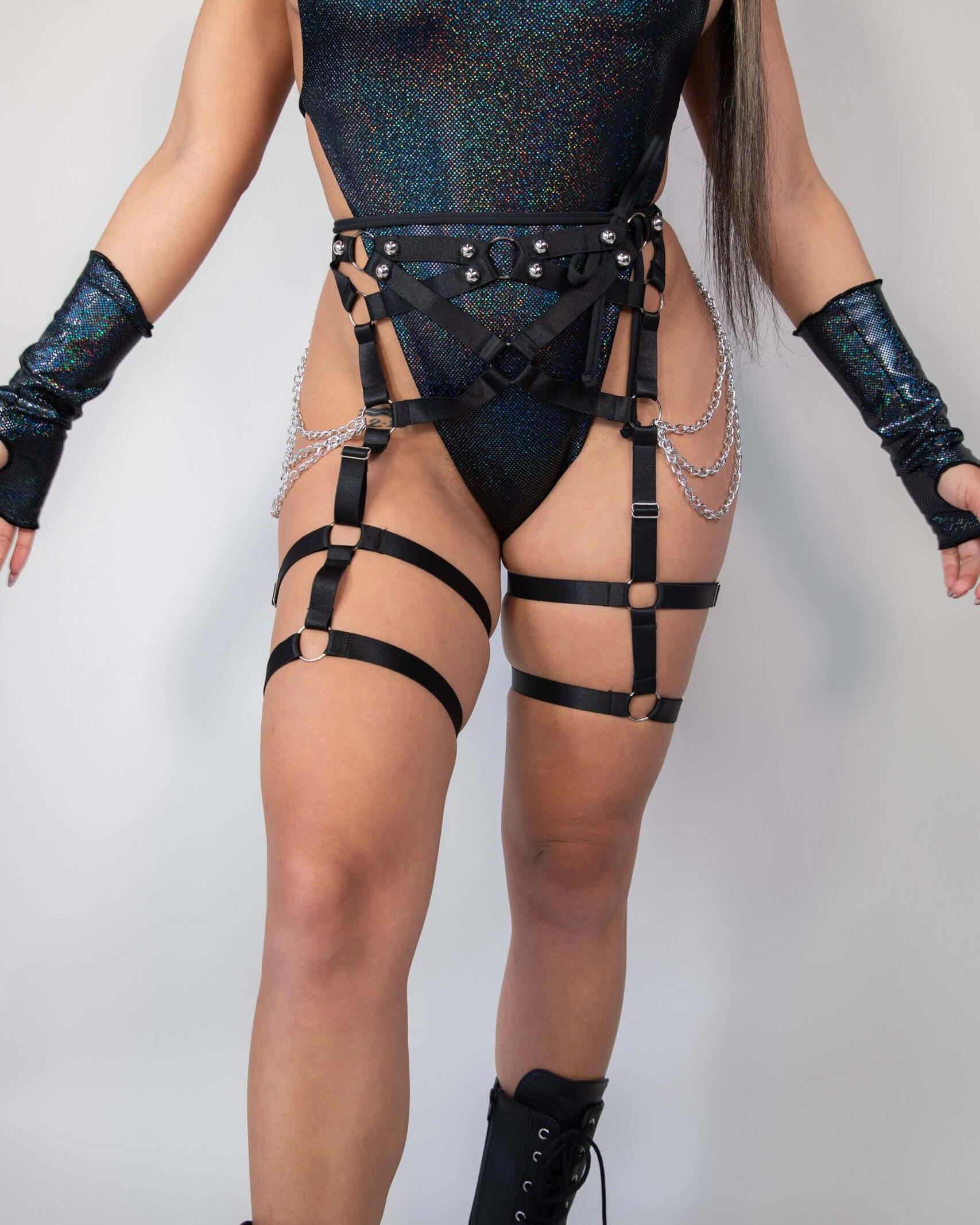 Strappy black Divinity leg harness with chains, worn over a shimmering bodysuit, perfect for rave outfits and bold fashion statements.