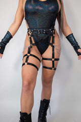 Strappy black Divinity leg harness with chains, worn over a shimmering bodysuit, perfect for rave outfits and bold fashion statements.