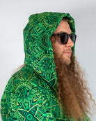 Model wearing green patterned Dominion Assassin Hood with oversized design and sunglasses, perfect for rave fashion.