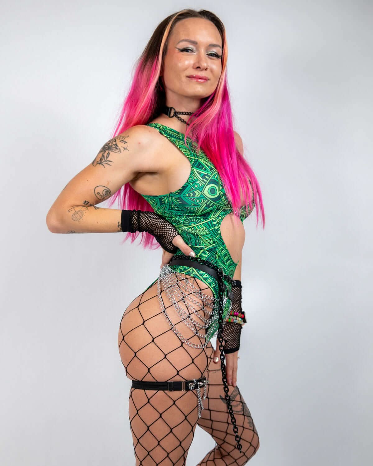 Model wearing a vibrant green rave bodysuit with unique cutouts and accessories, posing confidently.