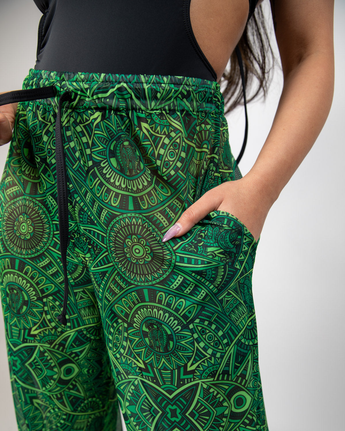 Dominion Mesh Lucy Pants in vibrant green with tribal print, showcasing pockets and a relaxed fit for rave bottoms.