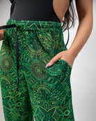 Dominion Mesh Lucy Pants in vibrant green with tribal print, showcasing pockets and a relaxed fit for rave bottoms.