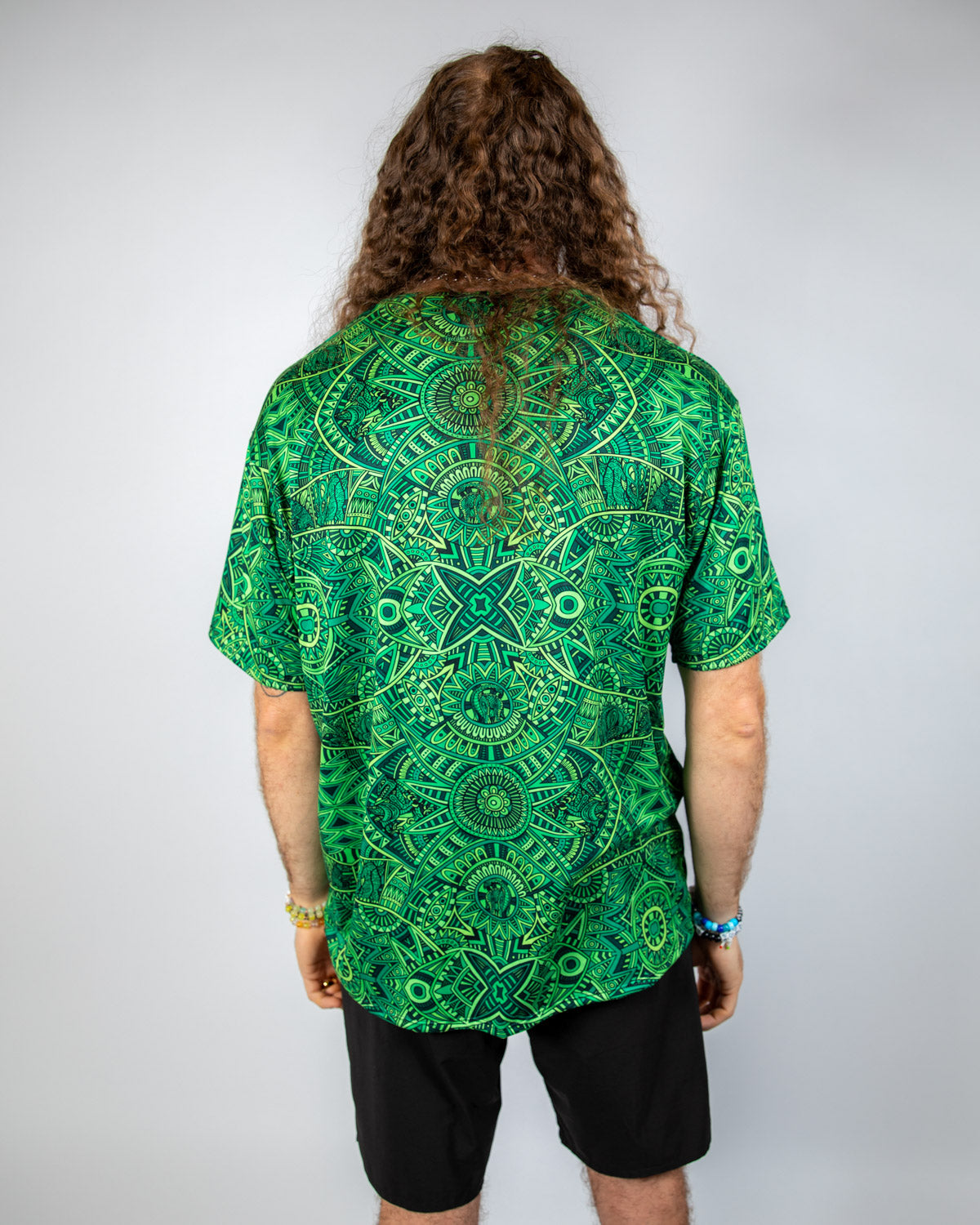 Back view of a man wearing a green psychedelic Rave T-Shirt with a bold pattern, showcasing relaxed oversized fit.