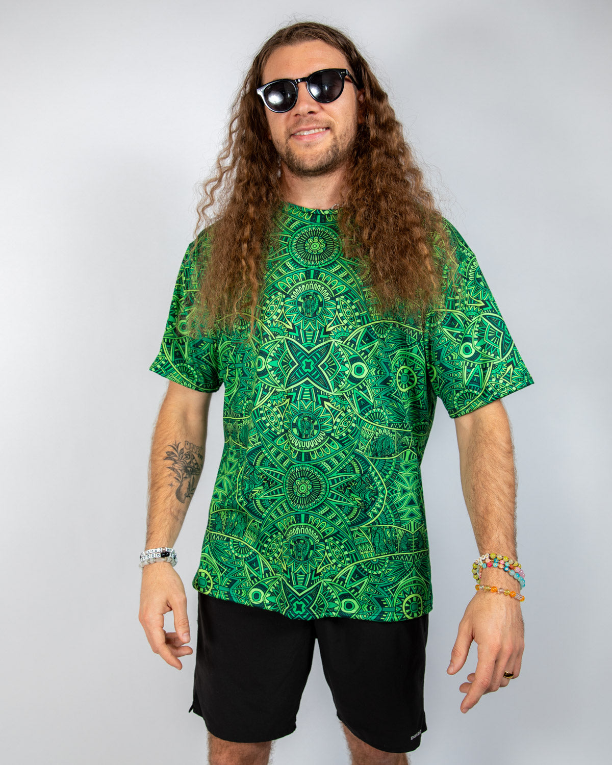 Man wearing a vibrant green oversized Rave T-Shirt with psychedelic patterns and sunglasses.