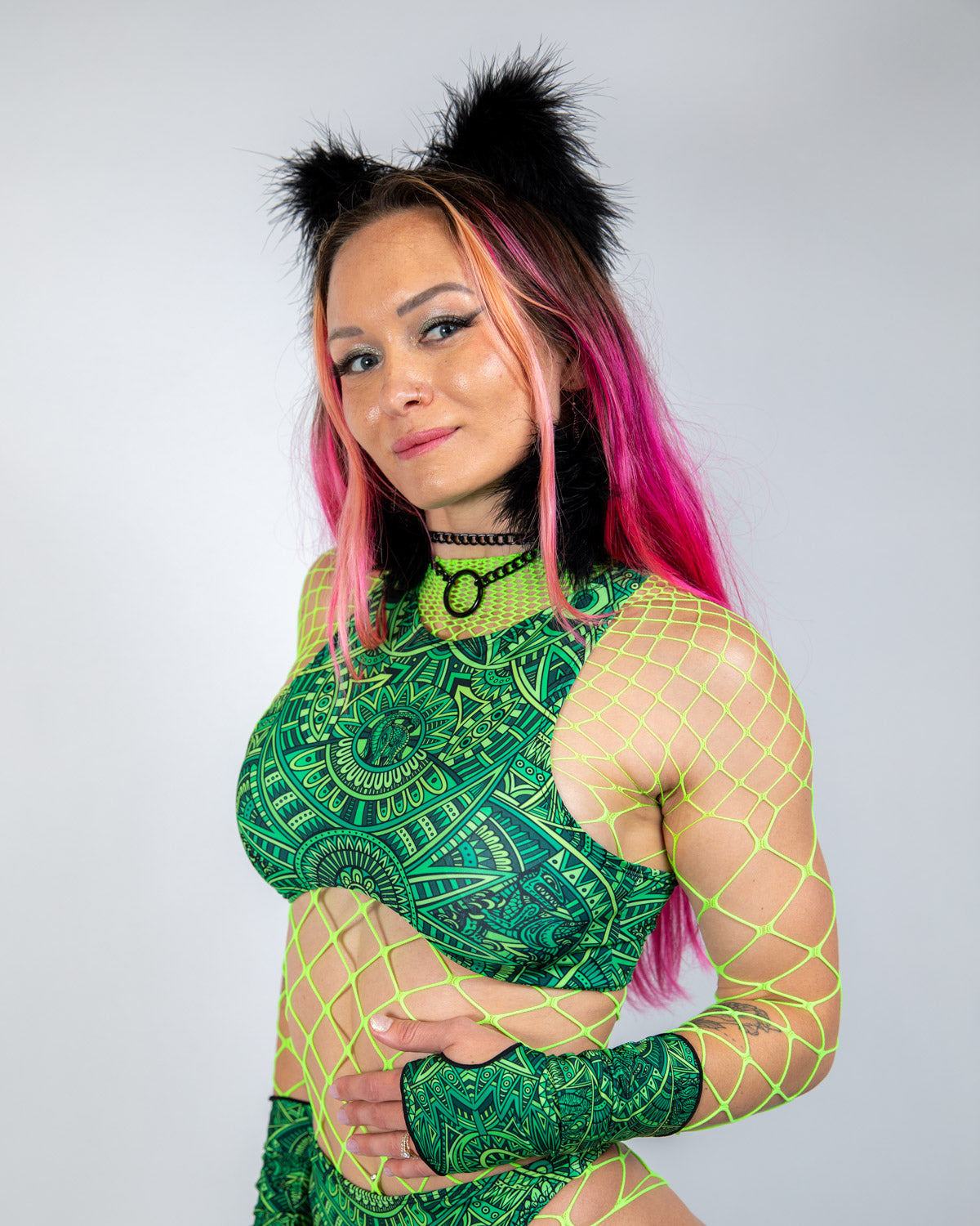 Model wearing a vibrant green rave top with underboob cut, fishnet details, and playful accessories, perfect for festivals.