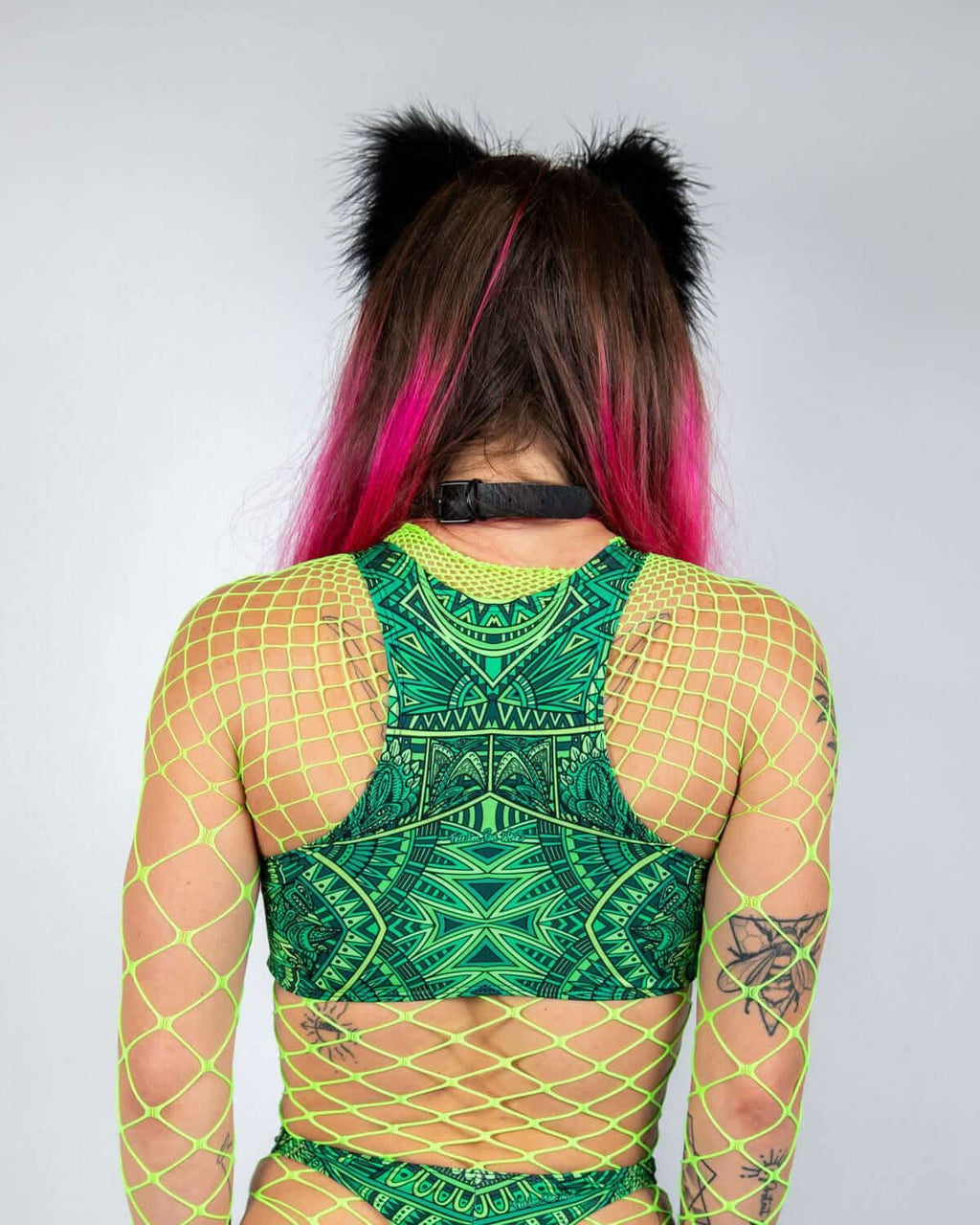 Back view of a model wearing a vibrant green rave top with fishnet detailing and cat ear accessories.