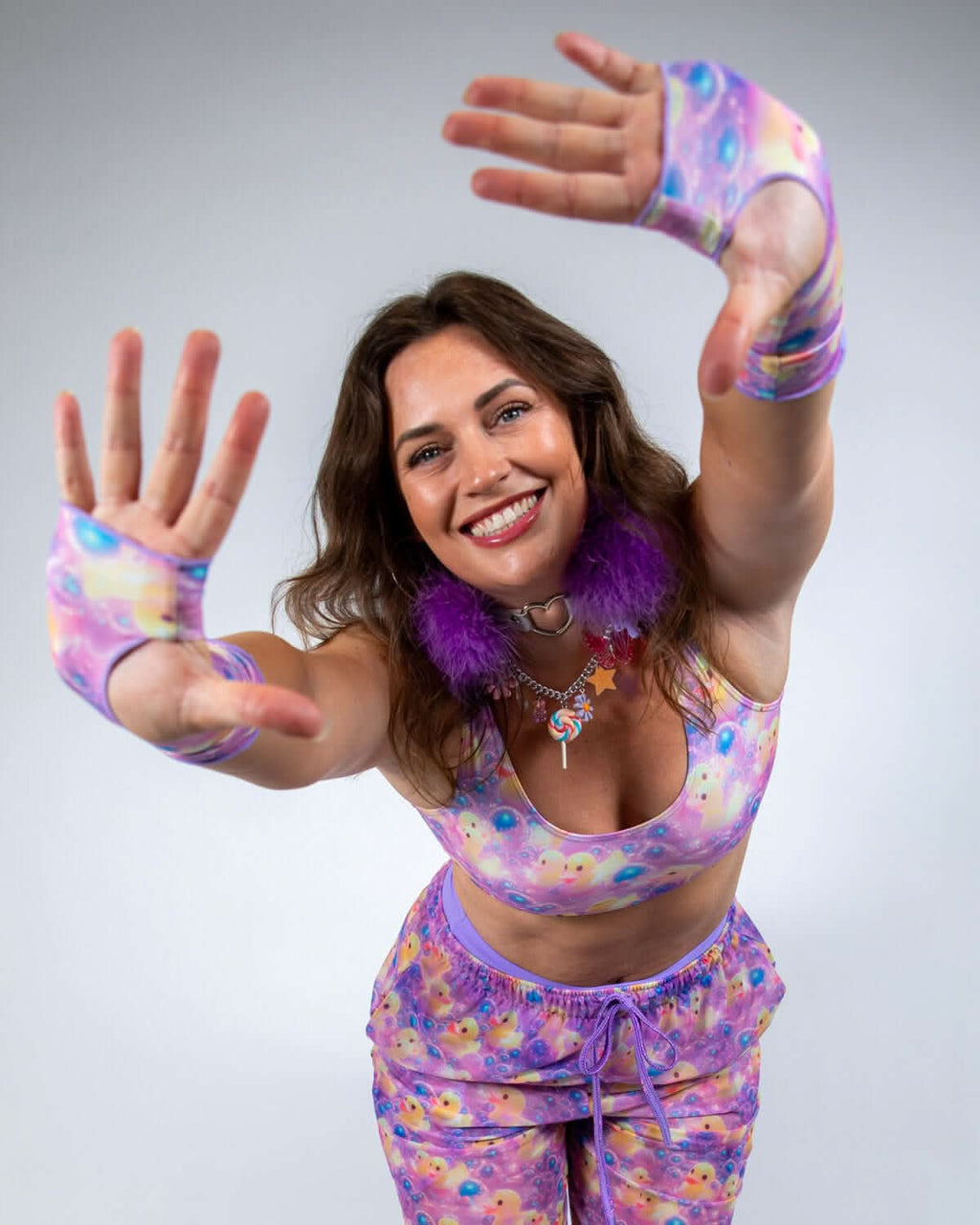 A model showcasing Duckies Gloves, vibrant fingerless arm warmers, perfect for rave outfits, paired with a matching outfit.