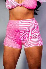 An up close photo of a woman wearing pink and white shorts with a matching crop top.