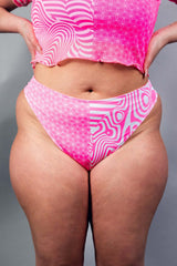 An up close photo of a woman wearing pink and white high waisted bikini bottoms.