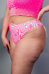 An up close photo of a woman wearing pink and white high waisted bikini bottoms. She is facing to the left.