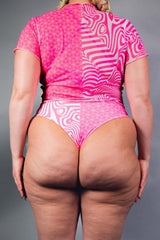 An up close photo of a woman wearing pink and white high waisted bikini bottoms. She is facing away from the camera.