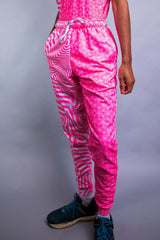 An up close photo of a man wearing pink and white joggers with a matching tank top tucked in.
