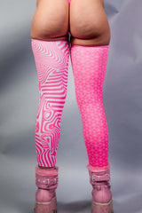 A photo of a woman's legs wearing pink and white leg sleeves that go up to her upper thigh. She is facing away from the camera.