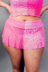 An up close photo of a woman wearing a pink and white mesh skirt and matching crop top.