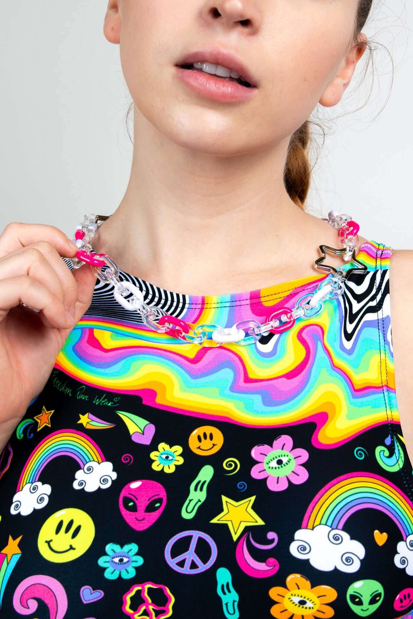 Close-up of a colorful rave outfit from Freedom Rave Wear, featuring vibrant psychedelic patterns and a star-themed chain necklace. Perfect for festivals.