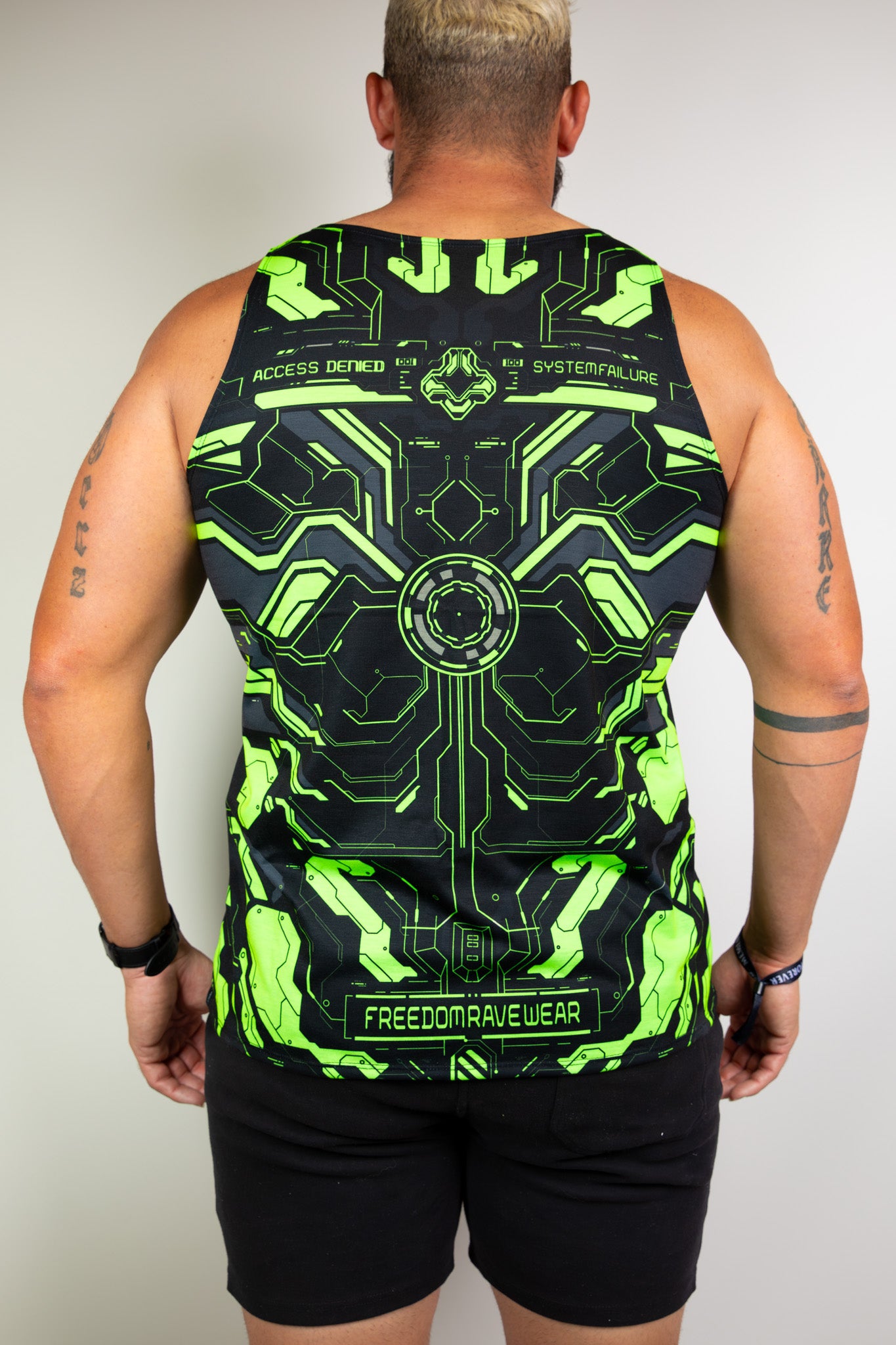 Model displaying back view of a neon green and black tech-themed tank top, perfect for raves. Freedom Rave Wear offers unique festival fashion.