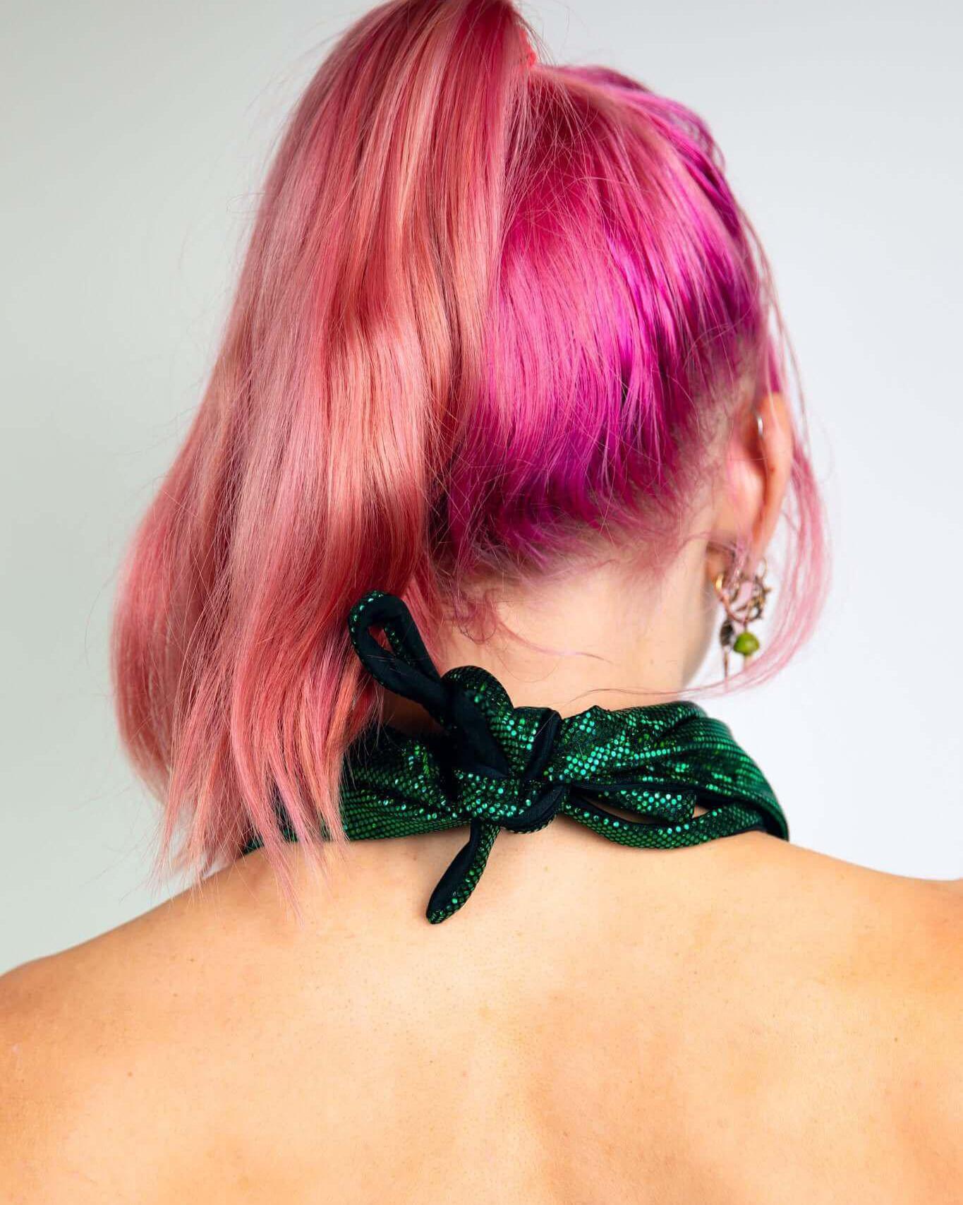 Pink-haired model wearing an emerald holo bandana styled as a neckpiece, showcasing versatile rave outfit accessory.