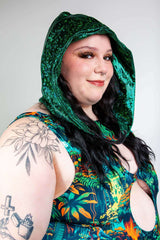 Model wearing an emerald holo assassin hood with chain, featuring a vibrant floral outfit, perfect for rave outfits.