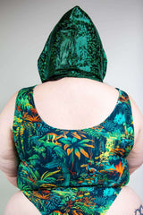 Back view of a model wearing an emerald holo hood with a colorful tropical print swimsuit, showcasing festival vibes.