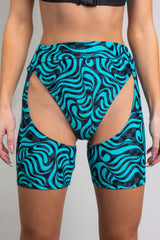 An up close photo of a woman wearing short chaps with a blue and black swirl design and matching bikini bottoms.