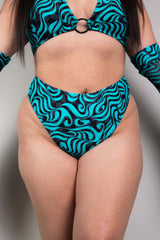 An up close photo of a woman wearing blue and black swirled bikini bottoms and a matching crop top.