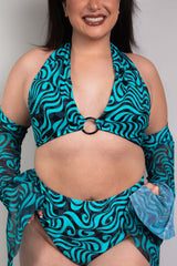 An up close photo of a woman wearing a blue and black swirled crop top with an o ring detail and matching bikini bottoms.