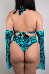 An up close photo of a woman wearing a blue and black swirled crop top and matching bikini bottoms. She is facing away from the camera.