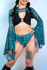A girl wearing blue and black swirl printed bell sleeves with a matching bikini bottom and a black crop top.