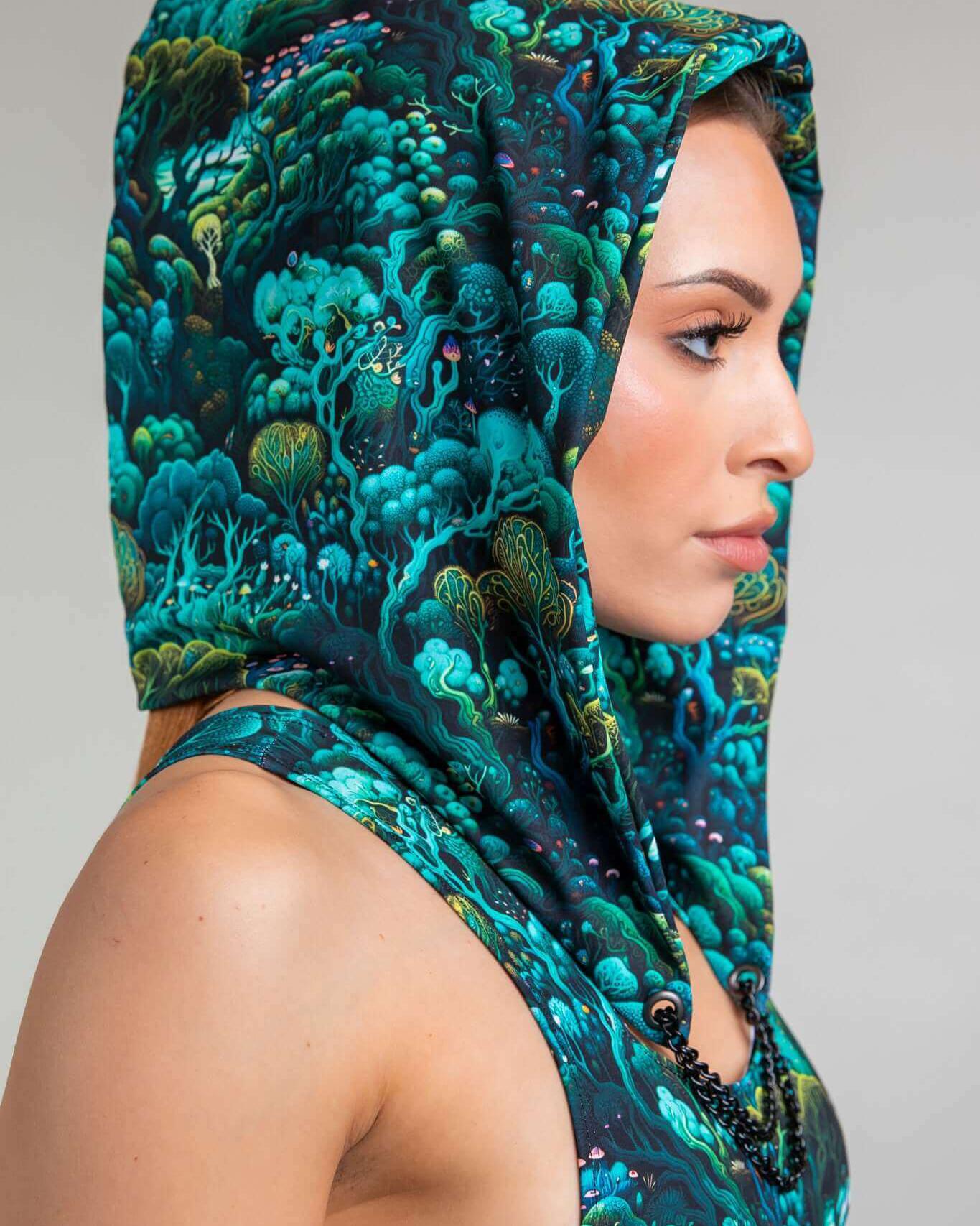 Profile view of a model wearing the Faewood Assassin Hood, showcasing its vibrant forest print design, perfect for rave outfits.