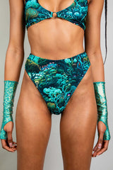Front view of a model in Freedom Rave Wear high-waisted bikini bottoms and matching top, featuring a psychedelic forest print and accented with shimmering arm sleeves.