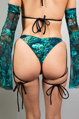 Rear close-up of a model in Freedom Rave Wear bikini, featuring tie-up sides and a psychedelic print, accented with matching arm sleeves, styled for a unique rave look.