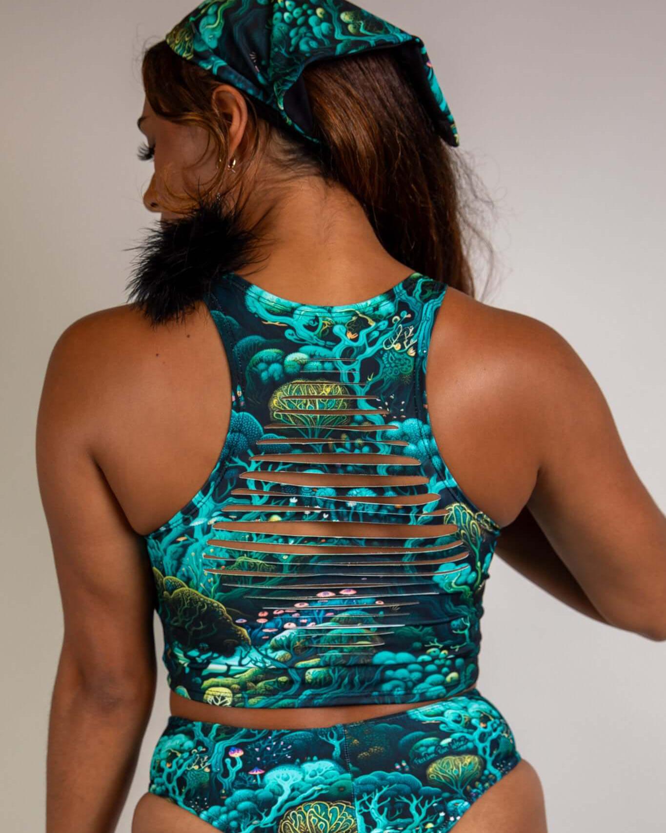 Woman wearing Faewood Slit Crop Top with unique slit design, featuring vibrant forest-themed pattern and matching accessories.