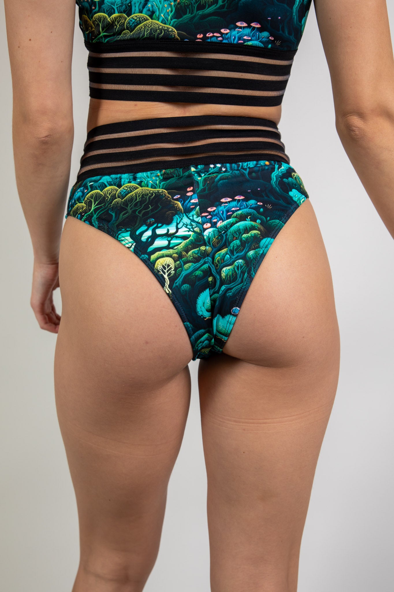 Faewood Sporty Bottoms in green and blue forest print, back view highlighting cheeky cut, high-waist fit, and mesh stripe waistband.