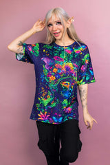 Model wearing a Freedom Rave Wear oversized tee featuring a vivid, psychedelic design of a floral goddess surrounded by butterflies and foliage.