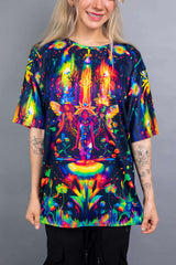 Model wearing a vibrant Freedom Rave Wear oversized tee with a fantasy forest design. The colorful shirt is paired with black pants.