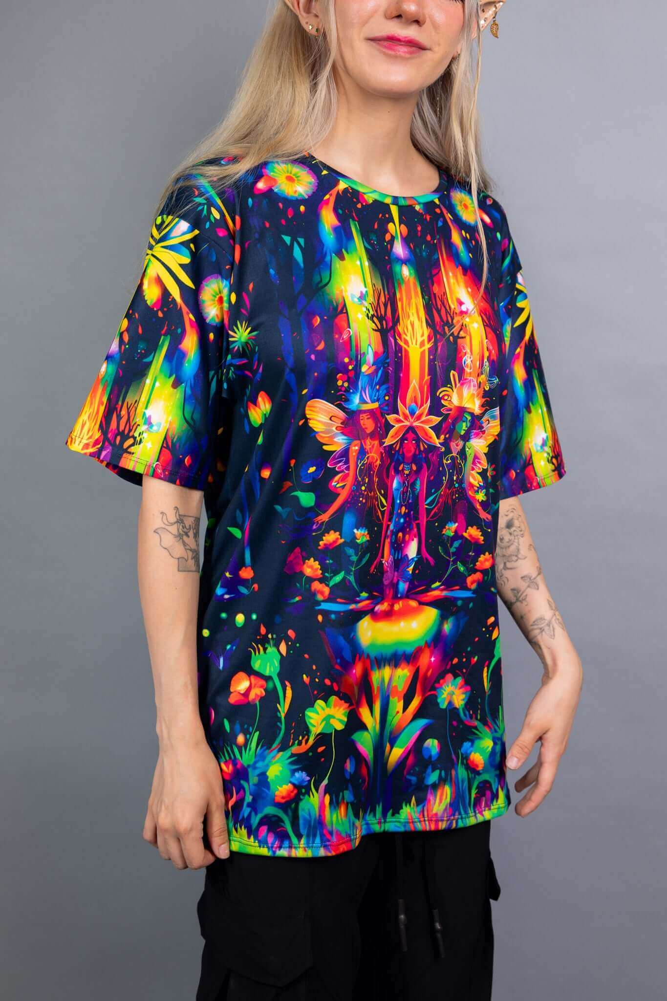 Model showcasing a Freedom Rave Wear oversized tee with a vibrant, fantasy forest design, paired with black pants. A bold and colorful festival look.