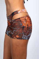 Close-up side view of a brown sheer mini skirt with a detailed pattern and side straps from Freedom Rave Wear.