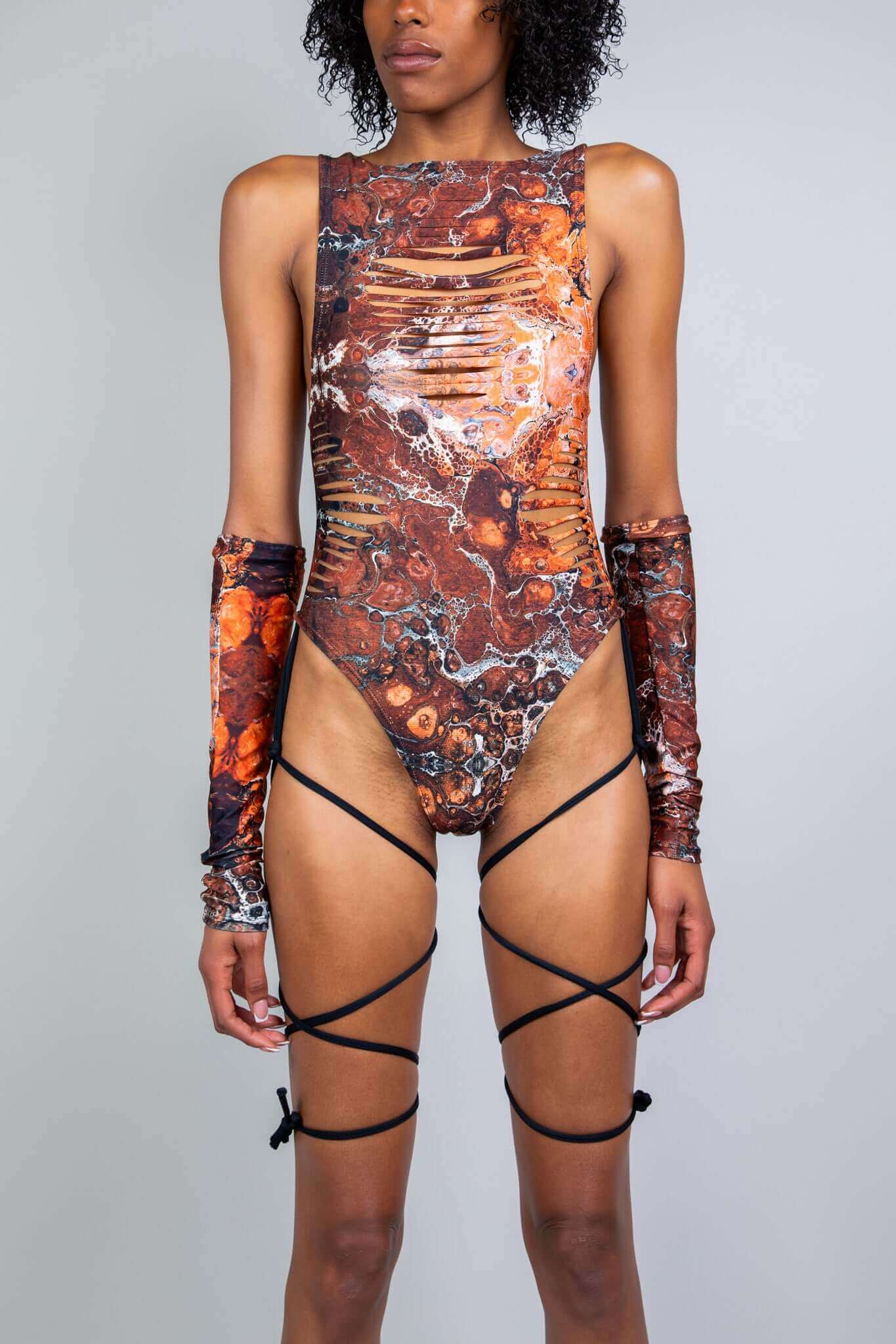 Model wearing a brown and orange marbled cut-out rave bodysuit with slits and string details from Freedom Rave Wear, perfect for festivals.